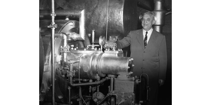 Willis Carrier w roku 1950, z pierwszym zbudowanym agregatem odśrodkowym, działającym następnie przez 27 lat w zakładach ceramicznych Onondaga w miejscowości Syracuse w stanie Nowy Jork. Korporacja Carrier odkupiła to urządzenie i przekazała je do kompleksu muze&oacute;w Smithsonian Institution w Waszyngtonie, gdzie znajduje się do dzisiaj. Fot. Carrier