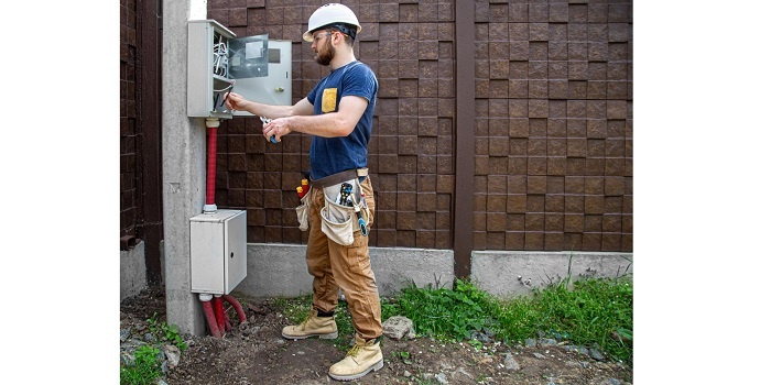 Elektryk podłączający prąd na działce. Fot. Envato