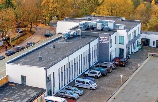 Widok z lotu ptaka na nowoczesny budynek Branżowego Centrum Umiejętności w Miastku z zaparkowanymi samochodami i otaczającą go zielenią